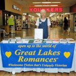 UPPAA A woman standing in front of a table with a sign for great lakes romances.
