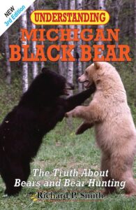 UPPAA Two black bears, one dark and one light-colored, stand facing each other on grass. The book cover reads: “Understanding Michigan Black Bear: The Truth About Bears and Bear Hunting” by Richard P. Smith. 3rd edition.